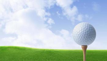 Golf ball on a green lawn on tee ready to be shot in natural background photo