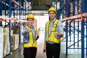 un hombre y una mujer con casco amarillo y un trabajador de almacén muestran el pulgar hacia arriba juntos para un trabajo exitoso con cara feliz. espíritu de equipo trabajando juntos en el almacén para completar el inventario de equilibrio, foto