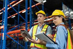 Caucasian two engineer team shipping order detail on tablet check goods and supplies on shelves with goods background inventory in factory warehouse.logistic industry and business export photo