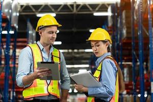 Male and Female Supervisors Holding Digital Tablet Talk about Inventory Check and Product Delivery in Retail Warehouse full of Shelves with Goods. Workers in Logistics Center. Portrait Shot photo