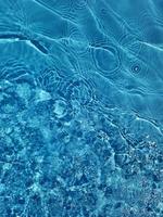 desenfoque de agua azul borrosa que brilla en el mar. fondo de detalle de agua ondulada. la superficie del agua en el mar, fondo del océano. ola de agua bajo el fondo de la textura del mar. foto