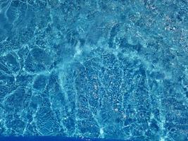 desenfoque de agua azul borrosa que brilla en el mar. fondo de detalle de agua ondulada. la superficie del agua en el mar, fondo del océano. ola de agua bajo el fondo de la textura del mar. foto