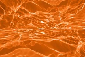 Defocus blurred transparent orange colored clear calm water surface texture with splashes and bubble. Trendy abstract nature background. Water wave in sunlight with copy space. Blue watercolor texture photo