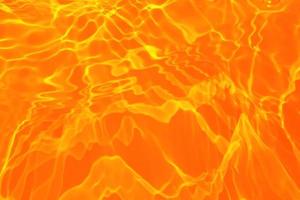 Defocus blurred transparent orange colored clear calm water surface texture with splashes and bubble. Trendy abstract nature background. Water wave in sunlight with copy space. Blue watercolor texture photo