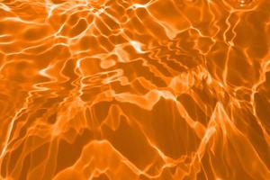 Defocus blurred transparent orange colored clear calm water surface texture with splashes and bubble. Trendy abstract nature background. Water wave in sunlight with copy space. Blue watercolor texture photo