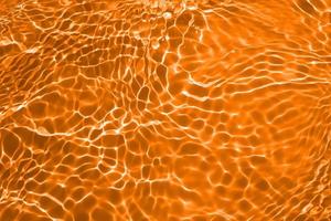 Defocus blurred transparent orange colored clear calm water surface texture with splashes and bubble. Trendy abstract nature background. Water wave in sunlight with copy space. Blue watercolor texture photo