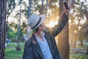 Asian man with mobile phone in forest tree nature - people in spring nature and technology concept photo