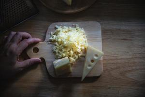 Woman preparing cheese for cook using cheese grater in the kitchen - people making food with cheese concept photo