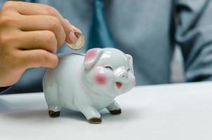 Businessman person hand holding coin money saving piggybank on table.Business finance account investment tax economy insurance and plan retirement concept. photo