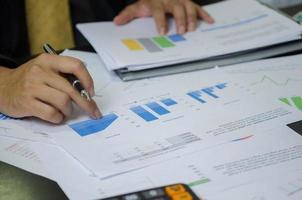 Businessman working in an office with a laptop with data documents graphs and charts marketing research statistics and financial development. photo