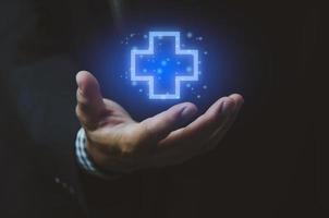 Cruz de seguro de icono de mano de hombre. pantalla virtual de símbolos médicos de atención médica. concepto de negocio. foto