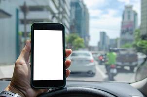 hombre que sostiene el teléfono inteligente móvil se burla de la pantalla blanca en el automóvil. foto