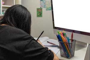 Asian student girl is writing homework and reading book at desk photo