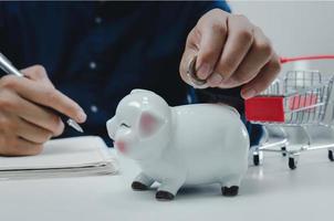 Business man hand holding coin money saving at piggy bank.Business economy management finance investment market and shopping concept. photo