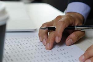 Businessman hands use pen to document business percentage figures. Finance and accounting analysis of economic and investment business concept. photo