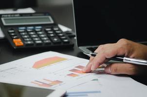 Businessman working in an office with a laptop with data documents graphs and charts marketing research statistics and financial development. photo