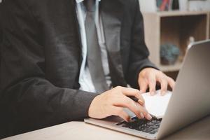 hombre persona usando teclado computadora portátil con pluma y libro en el escritorio. foto