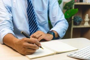 hombre mano sosteniendo pluma escribir nota diario en el libro. foto