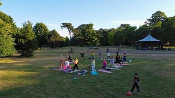 Group of Women Exercising Yoga Together in the Public Park at Sunset of Hot Summer, Aerial High Angle View of Wardown Park Luton England UK photo