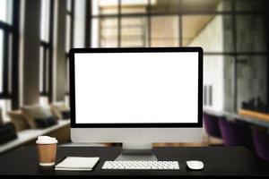 Computer monitor with white blank screen putting on white working desk with wireless mouse and keyboard over blurred vintage office photo