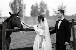 pareja joven el novio con un traje negro y la novia con un vestido corto blanco foto