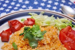 Fried rice with fried sausage served in a creamy dish with tomatoes and cucumbers. photo