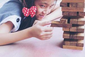 Asian kid is playing wood blocks tower game for practicing physical and mental skill photo