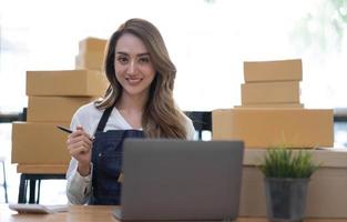 Retrato de mujer joven asiática SM trabajando con una caja en casa el lugar de trabajo.Propietario de una pequeña empresa de inicio, pequeña empresa emprendedora o empresa independiente en línea y concepto de entrega. foto