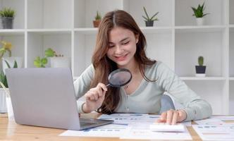 Business analyst using magnifying to review financial graphs, charts. Concept of Analyze return on investment and business analytics growth. photo