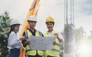 Three experts inspect commercial building construction sites and construction site holding blueprints