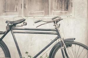 Old rusty vintage bicycle standing near concrete wall photo