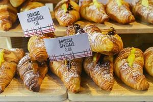 varios sabores de croissant o como en italia se llaman brioche en exhibición en una panadería en milán, italia con un precio y un cartel - albicocca significa mermelada en italiano foto