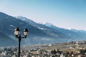 Selective focus of traditional lamppost and dining set table overlooking Sondrio, an Italian town and comune located in the heart of the wine-producing Valtellina region photo