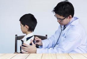 Sick asian boy being examined by male doctor over white background photo