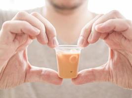 hombre mostrando un pequeño vaso de té helado foto