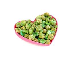 Green peas roasted with pink heart shaped cup isolated on white background photo