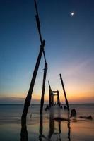 Sunset and reflections from the sea, decaying wooden bridges, Khao Pi Lai Phang Nga beach, Thailand photo