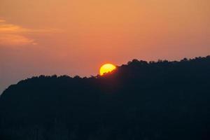 Sunrise behind the mountains, the shadows of the mountains, the orange sky with faint clouds. photo