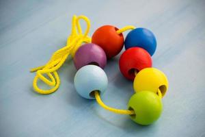 juguete infantil de desarrollo. bolas de madera de colores en una cuerda. Cuentas de bebé de madera de colores para collar. foto
