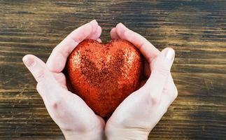persona con un corazón rojo hecho a mano en sus manos. amor. el 14 de febrero. día de San Valentín foto