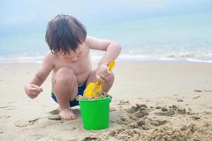 Wonderful boy plays with a bucket and a shovel in the sand on the seashore. photo