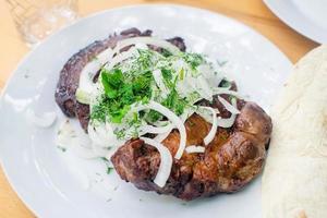 Appetizing grilled pork chop with onions and dill on the white plate. Juicy meat. photo