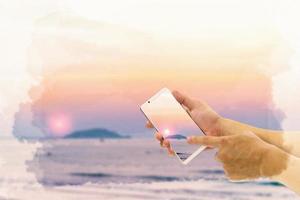 hand holding mobile smart phone with front the beach and sky  background ,watercolor digital painting style photo