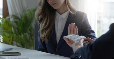 A professional Asian female lawyer or business legal consultant refuses a bribe or money from her client. graft or tribute payment concept photo