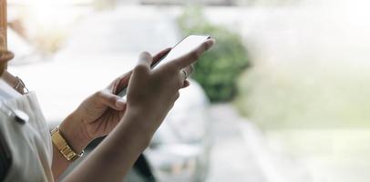 vista posterior de cerca de una mano de mujer usando un teléfono inteligente con pantalla en blanco acostado en un sofá en casa foto