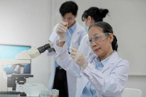 Health care researchers working in life science laboratory. Young female research scientist and senior male supervisor preparing and analyzing microscope slides in research lab. photo