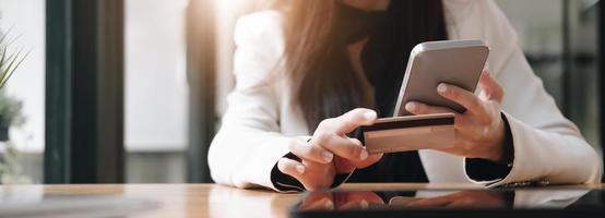 Close up female hands holding credit card and smartphone, young woman paying online, using banking service, entering information, shopping, ordering in internet store, doing secure payment photo