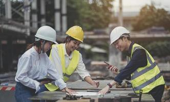 Asian woman civil engineer paper plan building architect wearing white safety helmet look at contruction site.Female foreman in a construction helmet, facemask, photo