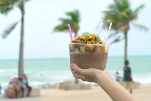 hands holding mixing chocolate shaved ice in a plastic cup with seascape background photo