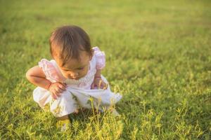 A little girl in the lawn looks at the spider closely at sunset. young naturalist Concept of observing nature of children. photo